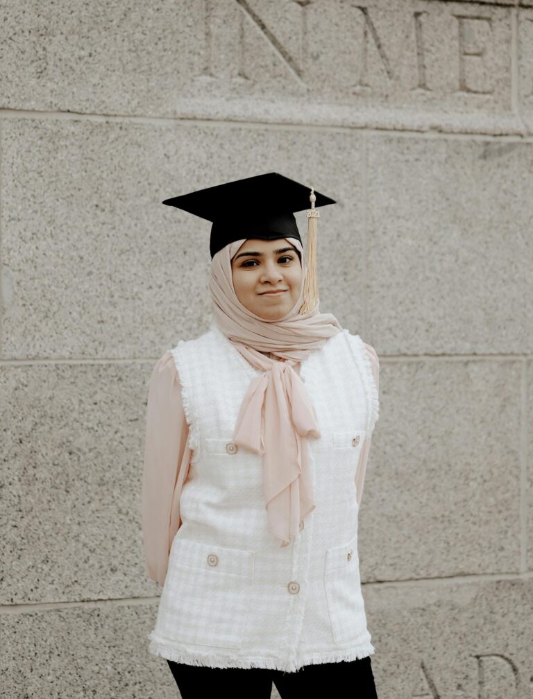 Muslim woman in hijab and mortarboard smiling at graduation ceremony.